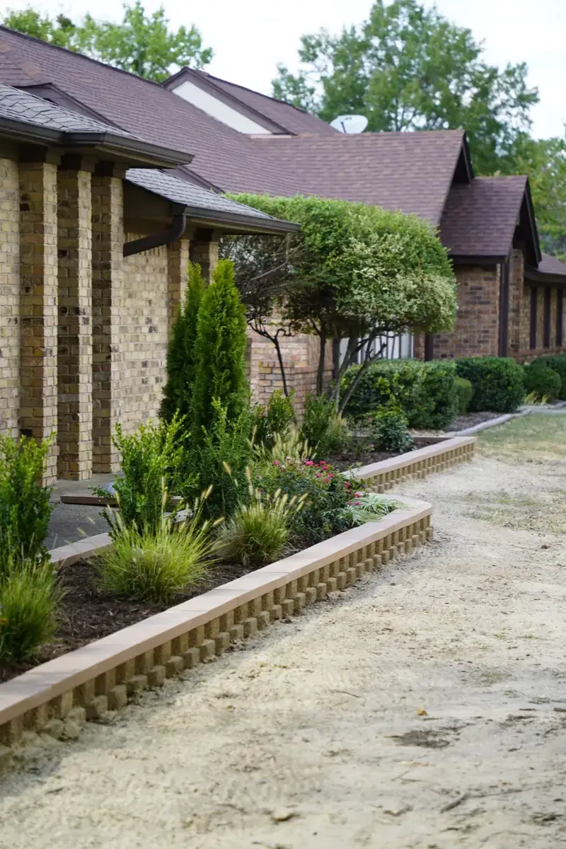 New planting bed with block border along a brick home