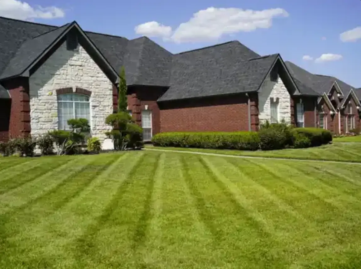 Freshly striped lawn in front of a brick and stone home